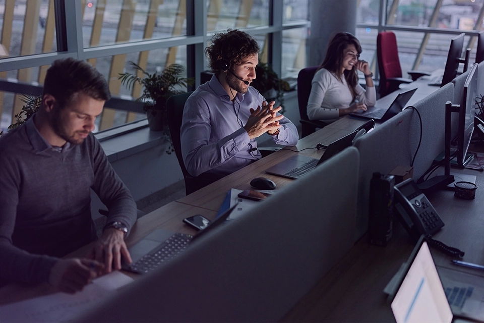 A group of three call center employees at their work stations.